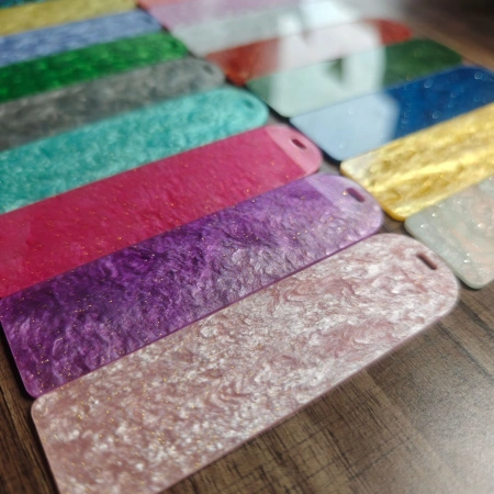 Batch of colorful glitter and pearl pattern acrylic bookmarks laid out on a wooden table