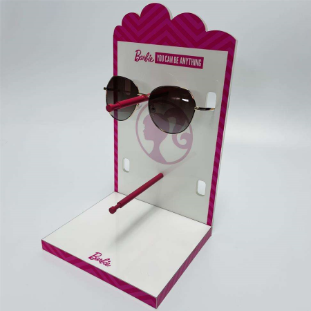 custom Barbie-branded acrylic sunglasses display stand featuring pink and white accents and holding a pair of stylish sunglasses